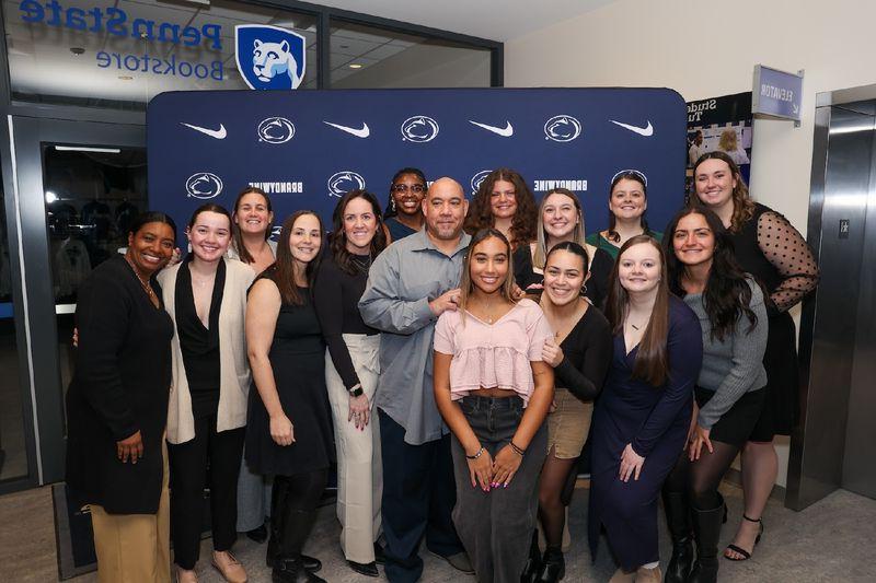 a group of people standing for a photo in front of a penn state backdrop